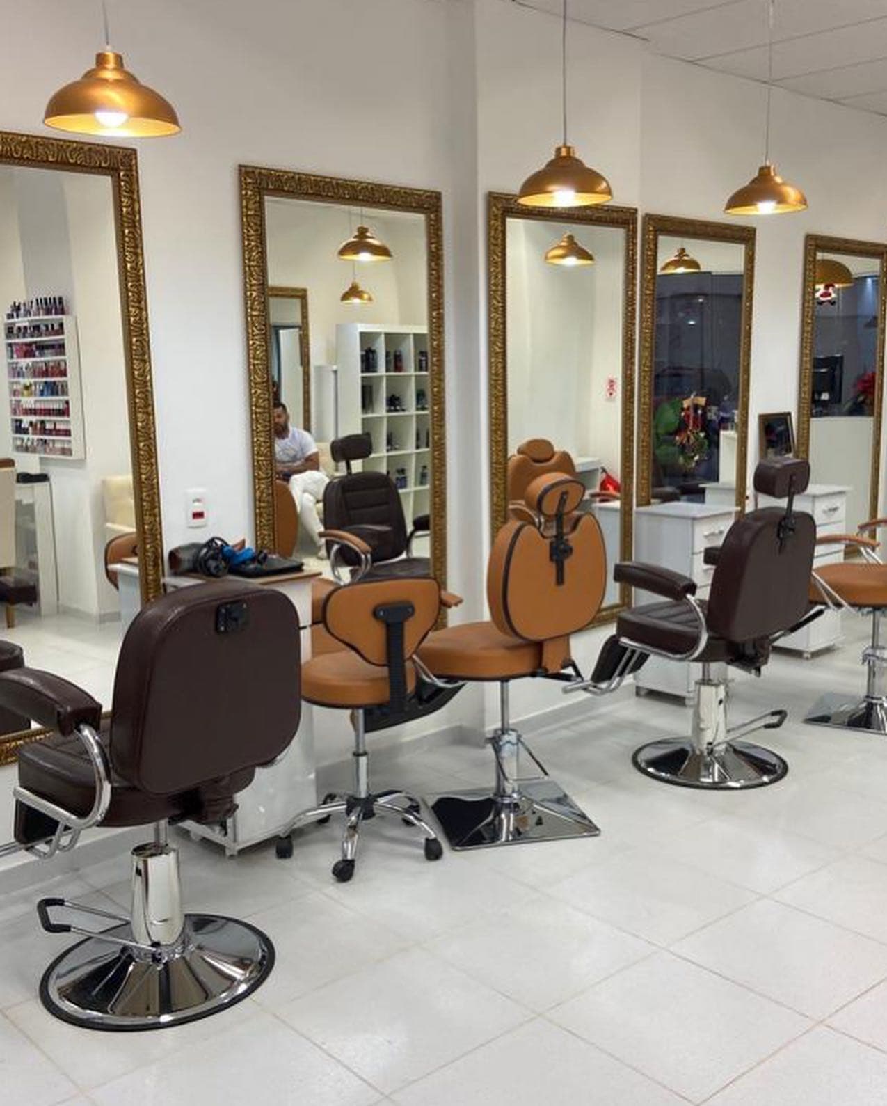 Salão do Zu Anjos Hair: cadeiras caramelo e marrons diante dos espelhos de moldura dourada, com pendentes dourados acesos